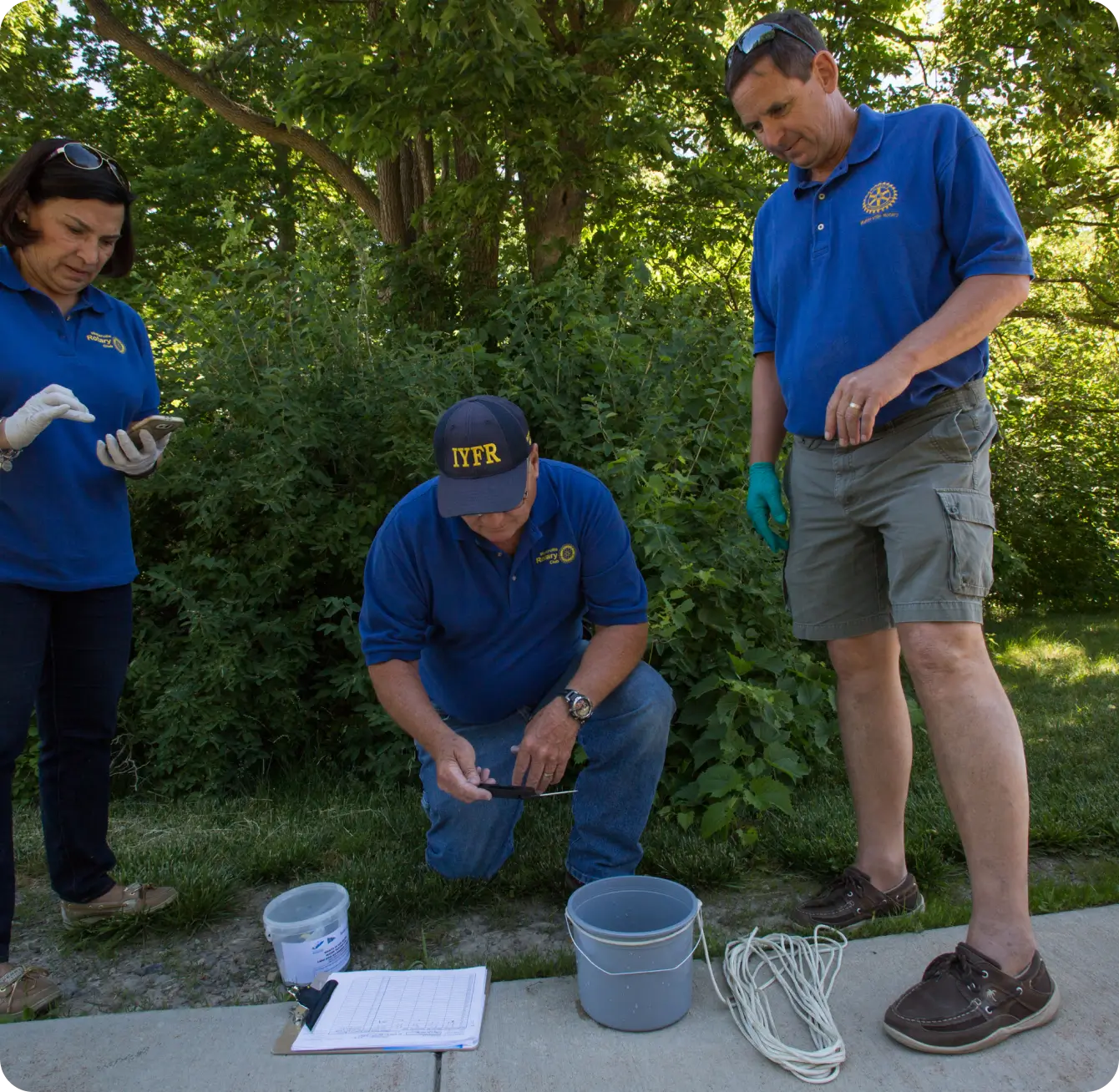Rotary employees gathered around water analysis equipment along a riverbank.