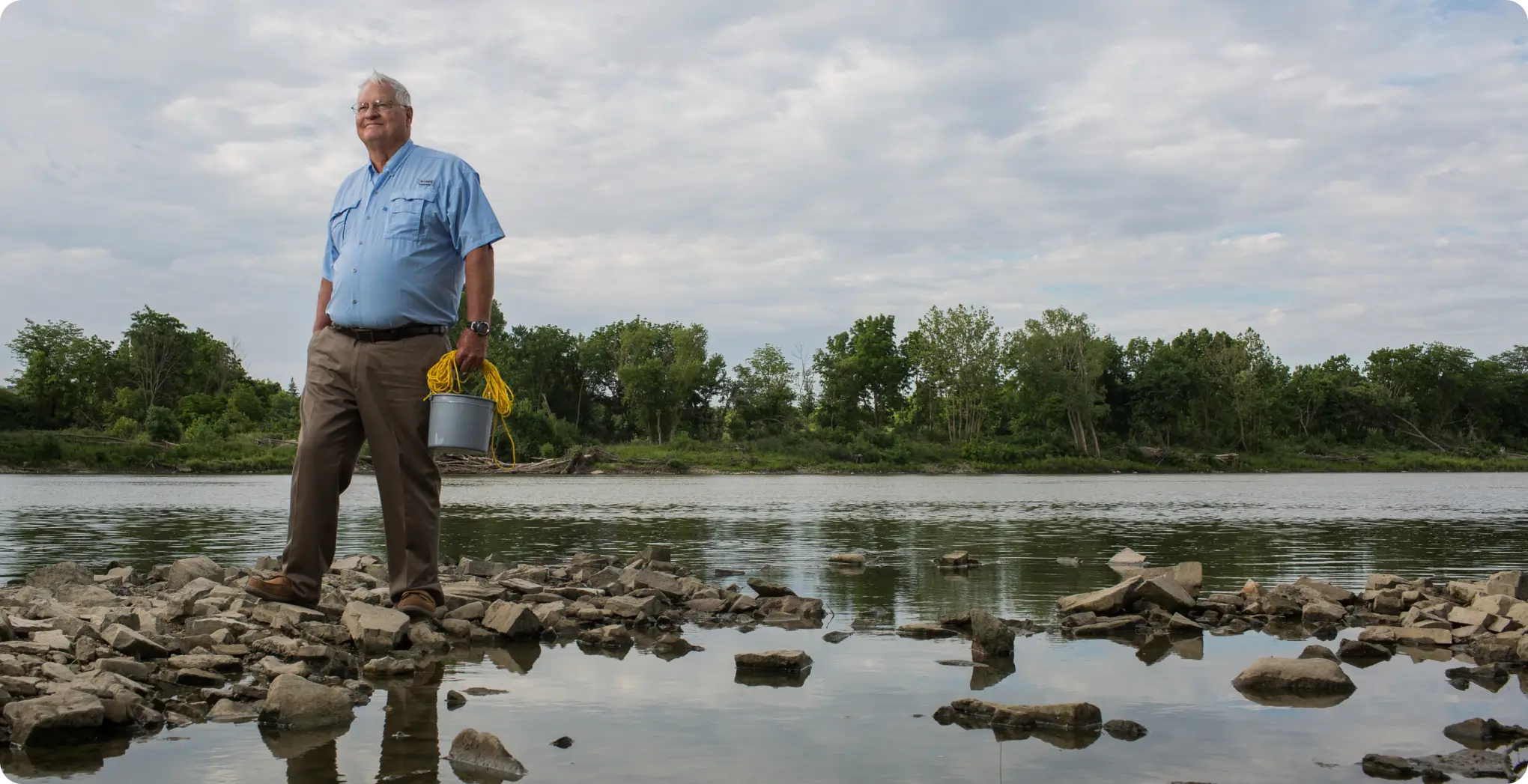Man stands alongside a river protected by the Community Action for Freshwater initiative.